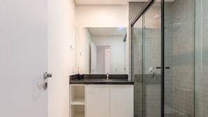 Ein modernes Badezimmer mit Duschkabine aus Glas, einem weißen Waschbecken und einem großen Spiegel.