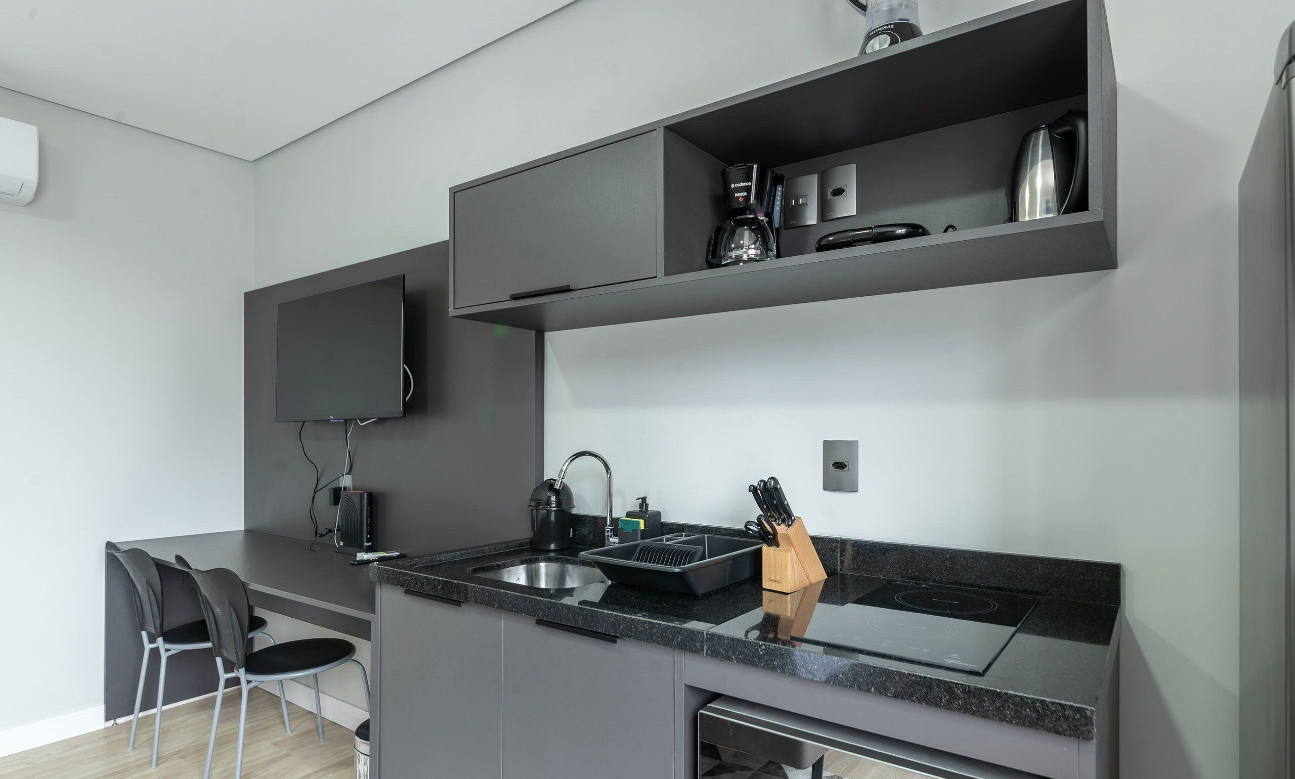 Una cocina moderna con estufa integrada, cafetera y televisor de pantalla plana montado en la pared.