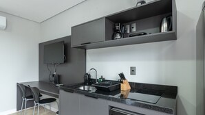 Eine moderne Küche mit Einbauherd, einer Kaffeemaschine und einem an der Wand befestigten Flachbildfernseher.