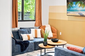 A living room with a sofa, a coffee table, and a painting of a beach scene. - Lovely Wynwood getaway! Large rooms (Miami)