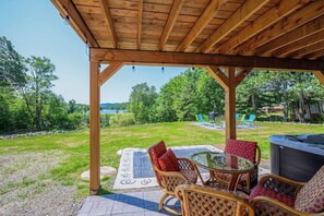 A covered outdoor seating area with wicker furniture and a hot tub.