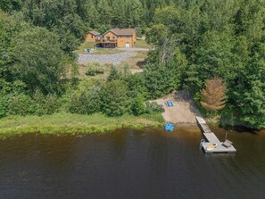 Una propiedad frente al lago con un muelle, una casa y un bote pequeño.