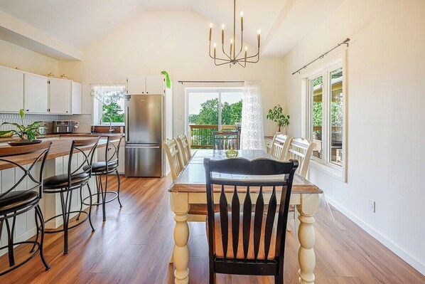 A kitchen with a dining area, wooden flooring, and a view of the outdoors.
