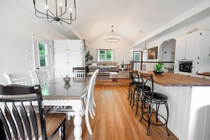 Una cocina amplia con comedor, piso de madera y muebles color blanco.