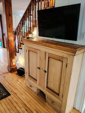 A wooden staircase with a TV mounted above a cabinet.