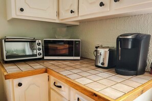 A kitchenette with a toaster, microwave, and coffee maker on a tiled countertop. - Le Refuge du Parc | 5 min Parc Mauricie (Maskinongé Regional County Municipality)