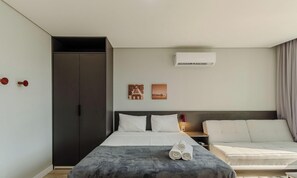 A modern hotel room with a bed, bedside table, and a sofa. - Studio in Cond. w/ Pool Near Redencao Park Tco0802 (Porto Alegre)