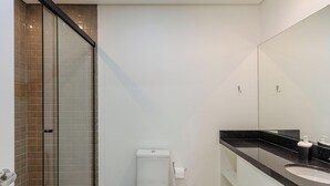 A modern bathroom with a glass shower enclosure, a white toilet, and a black countertop with a sink. - Studio in Cond. w/ Pool Near Redencao Park Tco0802 (Porto Alegre)