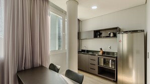 A compact kitchen with a built-in microwave, a coffee maker, and a refrigerator. - Studio in Cond. w/ Pool Near Redencao Park Tco0802 (Porto Alegre)