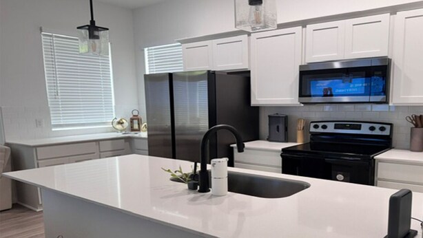 Una cocina moderna con una isla grande, electrodomésticos de acero inoxidable y armarios blancos.