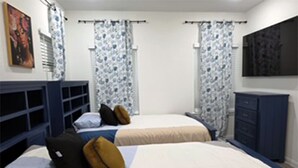 Un dormitorio con dos camas, un armario y cortinas.