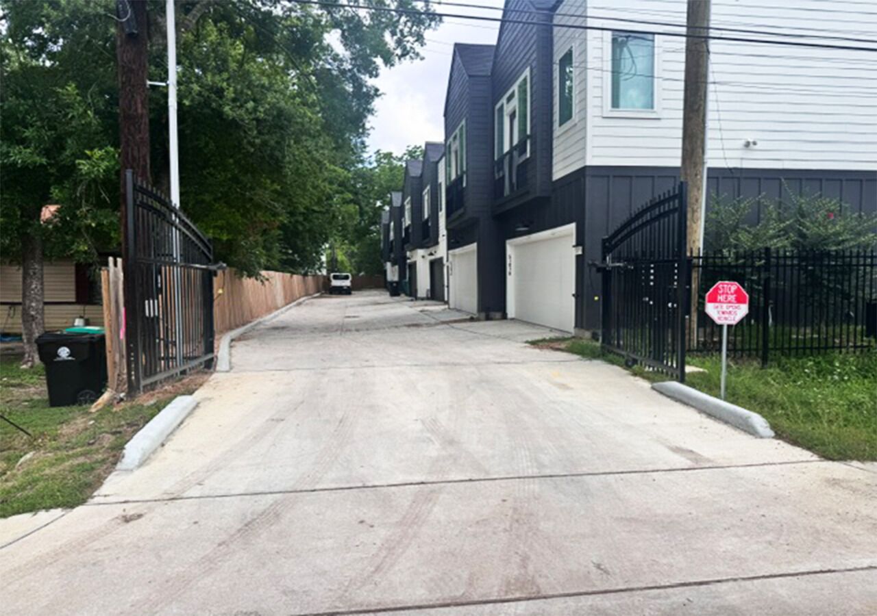 A residential street with houses, a stop sign, and a trash bin.