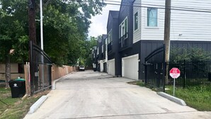 Una calle residencial con casas, una señal de alto y un contenedor de basura.