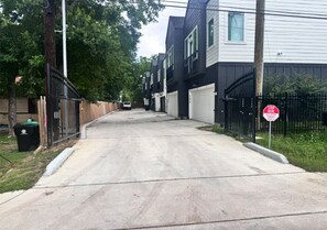 A residential street with houses, a stop sign, and a trash bin. - Quaint Duplex near everything medical center , downtown , pearland (Houston)