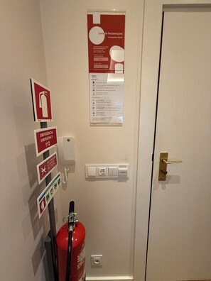 En dør med en brandslukker, nødopkaldsskilte og en stikkontakt.