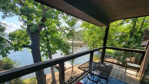 Eine überdachte Terrasse mit Blick auf einen See und Bäume.