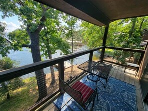 Eine überdachte Terrasse mit Blick auf einen See und Bäume.