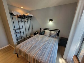 A bedroom with a bed, a wardrobe, a bedside table, and a wall-mounted light fixture. - Lone Oak Point 15 - Two Bedroom Apartment, Sleeps 6 (Sunrise Beach)
