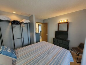 Una habitación de hotel con cama, armario, televisor y espejo.