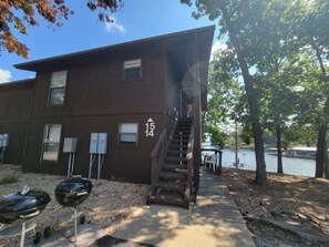 A two-story building with a visible staircase leading to the upper floor. There are two mailboxes and a grill outside. - Lone Oak Point 15 - Two Bedroom Apartment, Sleeps 6 (Sunrise Beach)