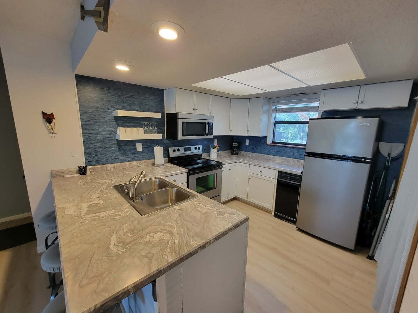 A modern kitchen with a central island, built-in appliances, and a window providing natural light.