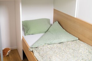A small, single-bed room with a wooden headboard and a plain white wall. - Peaceful 2-bedroom apartment in Bled's remote area perfect for relaxing (Bled)