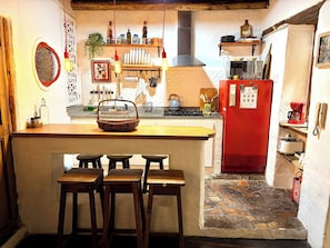 A kitchen with a red refrigerator, wooden stools, and a hanging light fixture. - Iechie Historic Colonial Stay in La Candelaria (Bogotá)