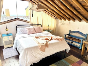 A bedroom with a bed, bedside table, lamp, and a view of the outside. - Iechie Historic Colonial Stay in La Candelaria (Bogotá)