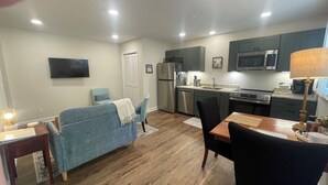 A compact living space with a kitchenette, a sofa, a dining table, and a TV mounted on the wall. - Spacious 1-Bedroom Duplex Vance Villa in UPTOWN Lexington (Lexington)