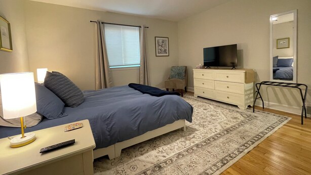 A bedroom with a bed, nightstand, lamp, TV, dresser, mirror, and a ceiling fan. - Spacious 1-Bedroom Duplex Vance Villa in UPTOWN Lexington (Lexington)