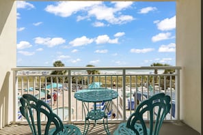 A balcony with a view of a beach and pool area, featuring a table and chairs. - North Myrtle Beach Oceanview Condo (North Myrtle Beach)