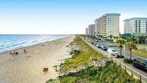 Un hotel frente a la playa con un largo paseo marítimo, acceso directo a la costa y un área de estacionamiento.