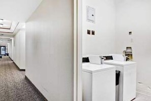Ein Hotel-Flur mit einer Wäscherei, darunter eine Waschmaschine und ein Trockner, sowie ein Empfangsbereich.
