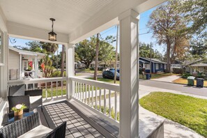 A covered porch with outdoor furniture, a view of a residential street, and a clear sky. - Haya Hideaway - Central - Cozy & Quiet (Tampa)