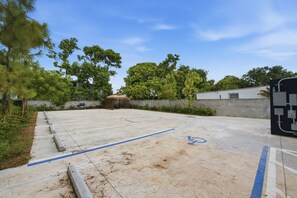 A parking area with a handicap parking space, a building in the background, and surrounding greenery. - Cozy Fun and Vibrant Central Wynwood! King Bed! (Miami)