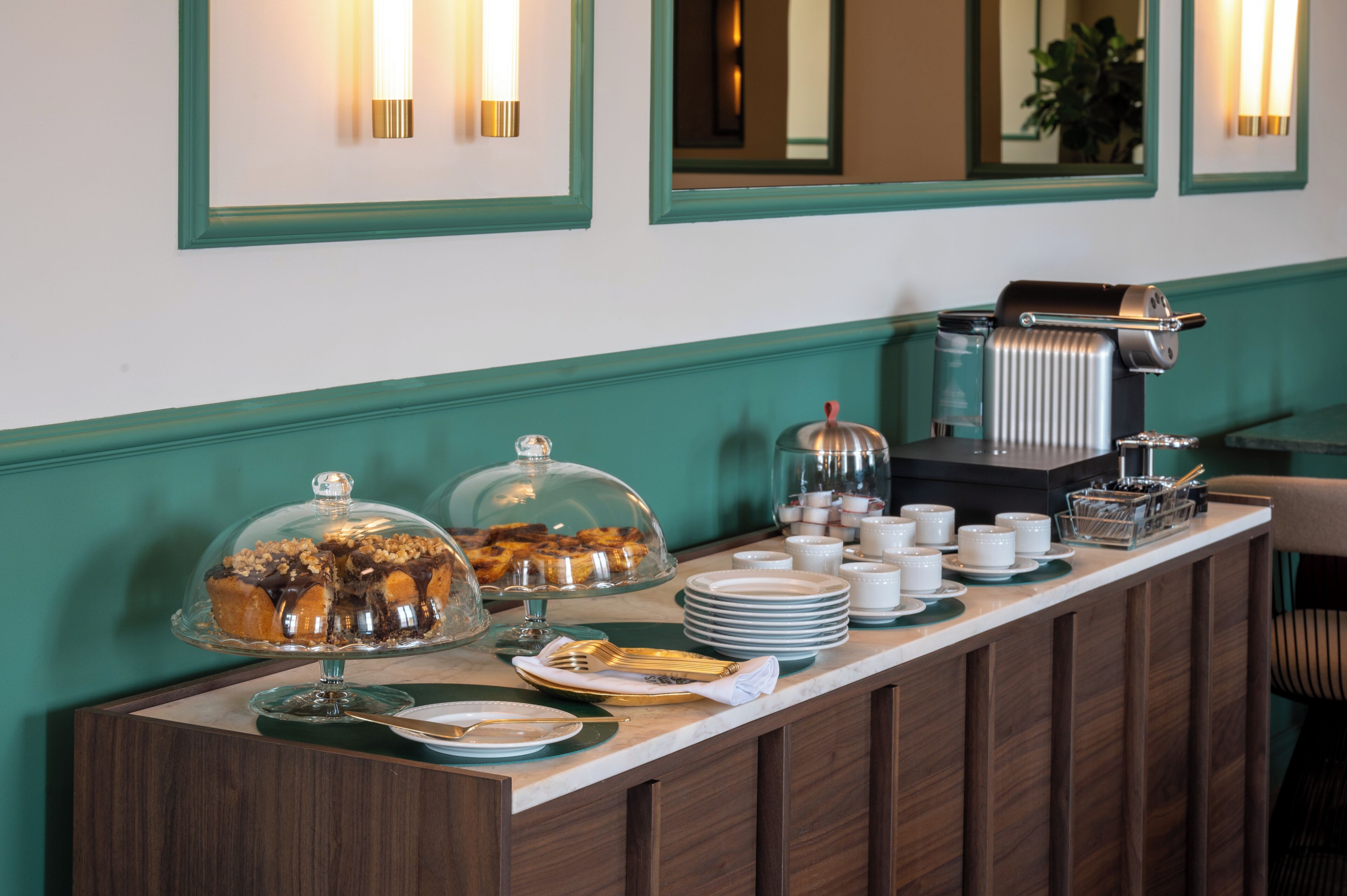A buffet setup with covered dishes, plates, and a coffee machine.