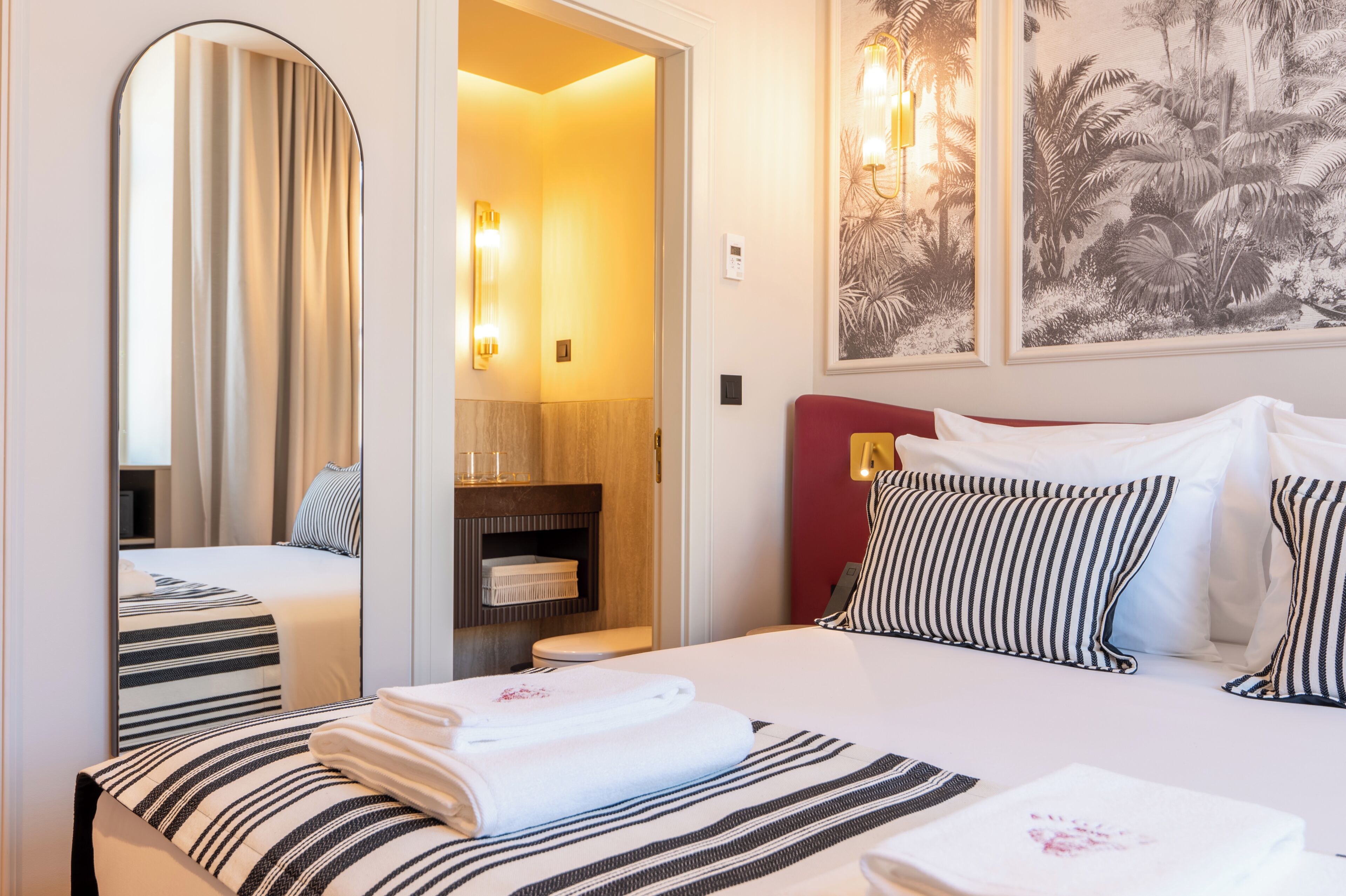 Una habitación de hotel con cama, baño y espejo.