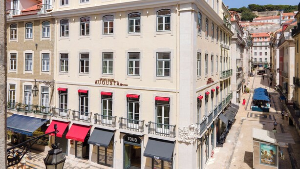 A multi-story hotel with a prominent 'AUGUSTA' sign, balconies, and storefronts with awnings. - Augusta Grand Hotel (Lisbon)