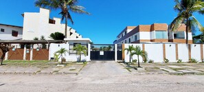 A gated residential area with modern buildings, palm trees, and a clear sky. - COPFL0110 - Cond Recanto do Flamengo (Salvador)