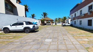 A paved courtyard with a white pickup truck and a white car parked on the side. - COPFL0110 - Cond Recanto do Flamengo (Salvador)
