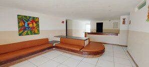 A hotel room with a brown sofa, a small table, and a colorful abstract painting on the wall. - COPFL0110 - Cond Recanto do Flamengo (Salvador)