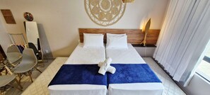 Ein Hotelzimmer mit einem Bett, zwei Nachttischen, einem Sessel, einer Wanddekoration und einem Fenster mit Vorhängen.