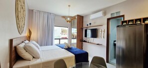 Quarto de hotel com cama, escrivaninha, televisão e minibar.