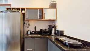 A compact kitchenette with a refrigerator, microwave, coffee maker, and a small sink. - COPFL0110 - Cond Recanto do Flamengo (Salvador)