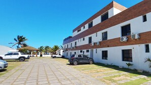 A multi-story building with a brick facade, air conditioning units, and numbered parking spaces. - COPFL0110 - Cond Recanto do Flamengo (Salvador)