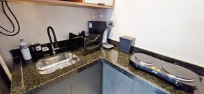 Uma cozinha compacta com pia, cafeteira, torradeira e balança.