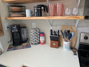Una cocina con cafetera, licuadora, botella de leche para café y un juego de cuchillos.
