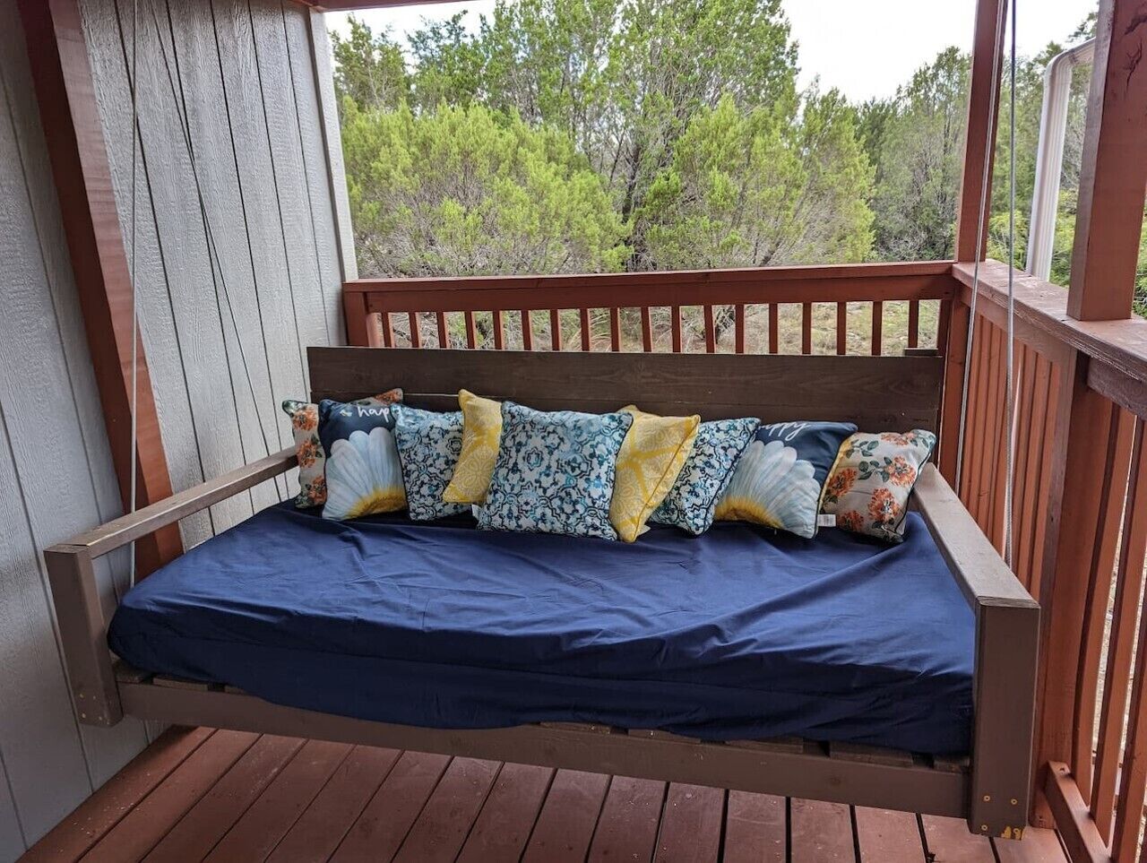 Un ponte di legno con un letto singolo, completo di materasso blu e cuscini decorati.
