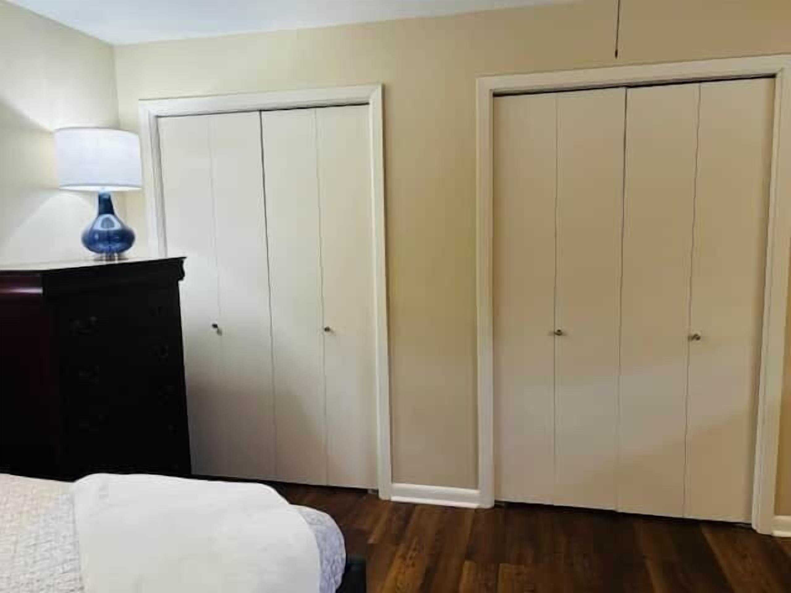 Un dormitorio con cama, cómoda, dos armarios y lámpara.