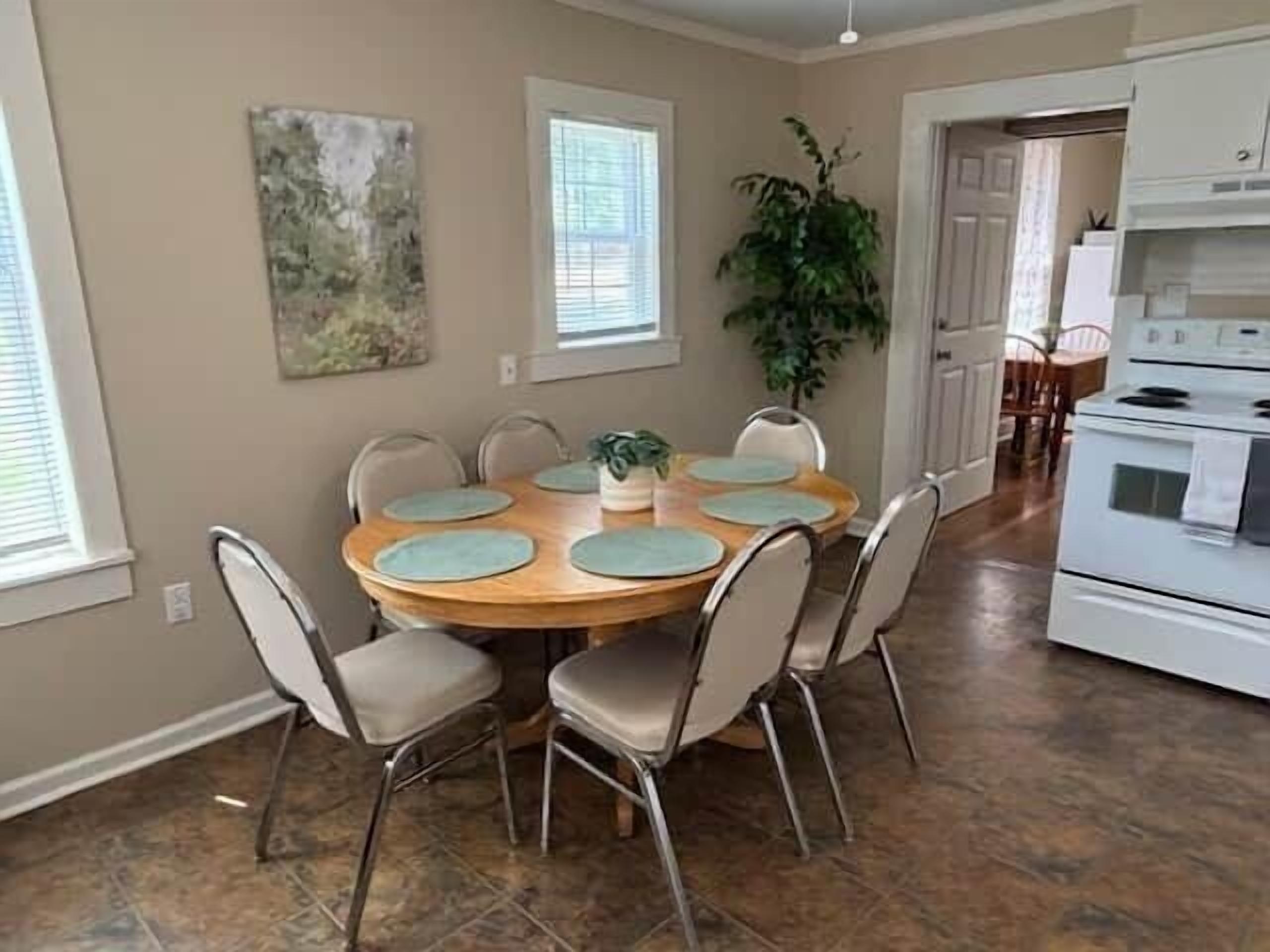 A dining area with a round table, chairs, and a potted plant.